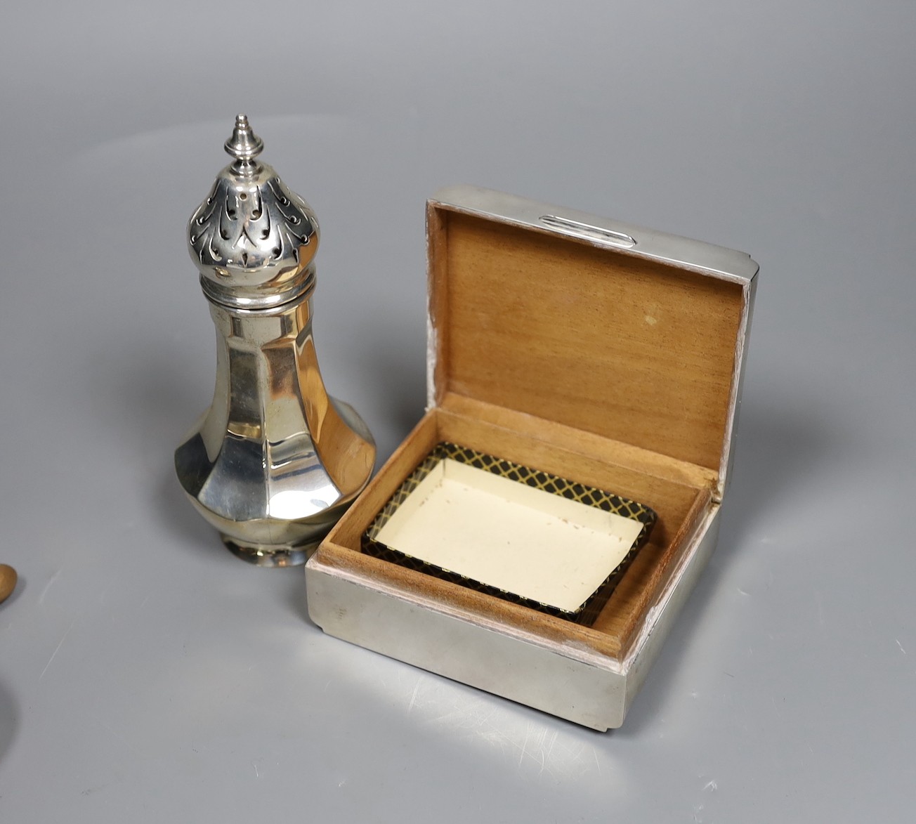 A George V engine turned silver mounted cigarette box, a similar sugar caster and later silver tea strainer and small dish.